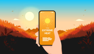 Extreme heat weather warning displayed on a smartphone screen against a hot summer landscape, representing UK heatwave alerts and workplace preparedness.